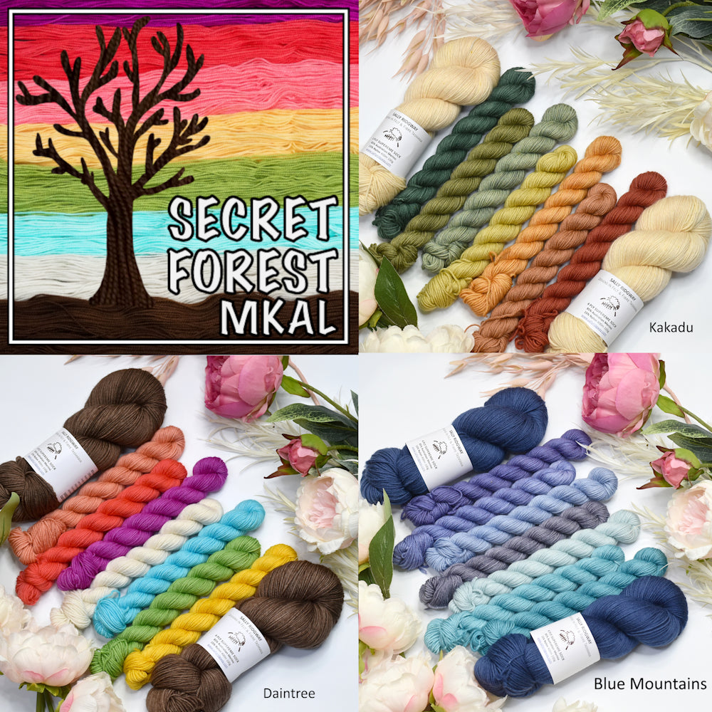 secret Garden hand dyed yarn kits for knitting displayed with flowers and a tree with rainbow colours behind it