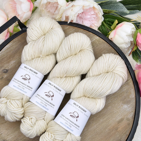3 skeins of cream hand dyed knitting yarn lying on a tray with flowers Shop hand dyed yarn online, Felt and Fibre Online